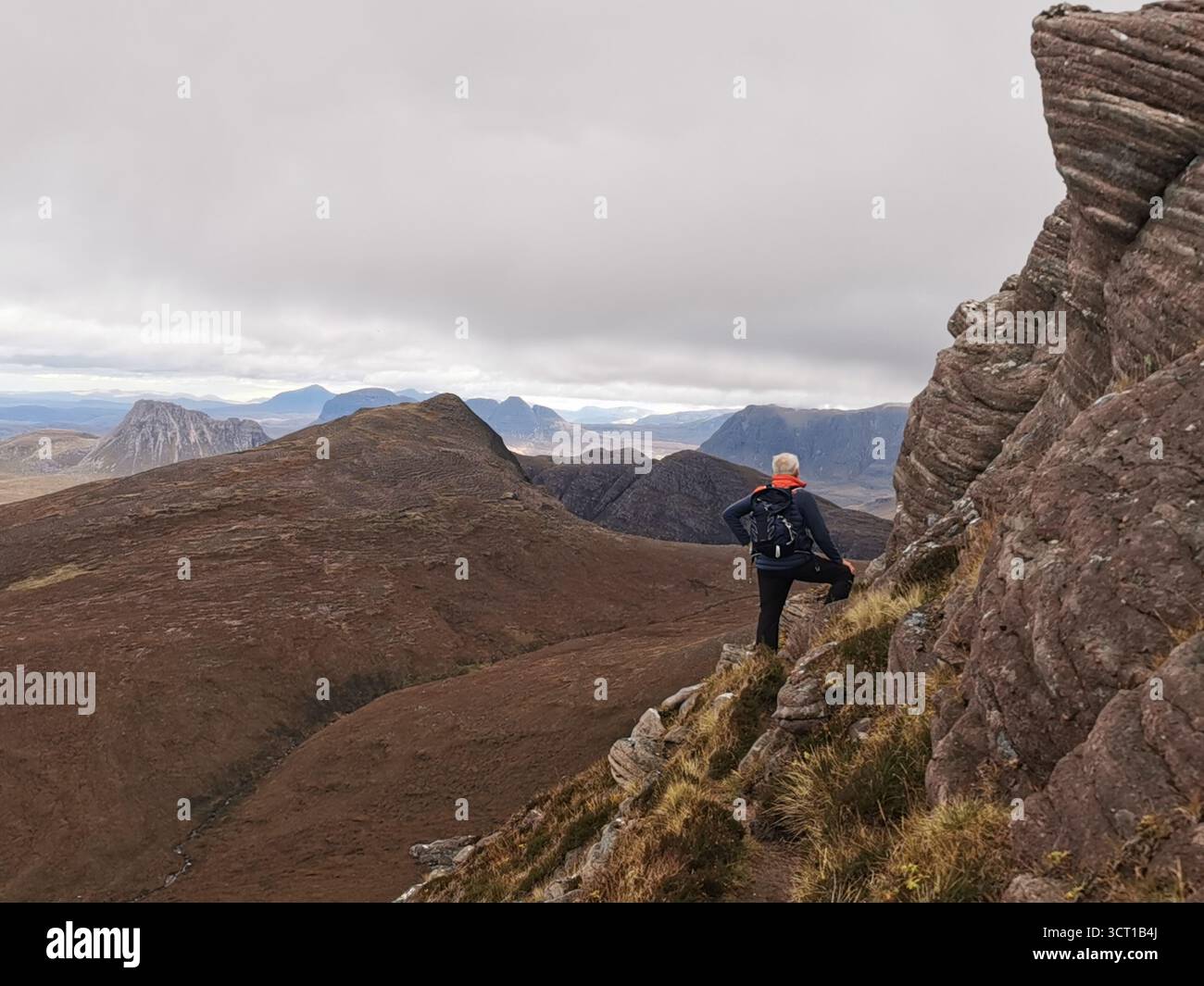 Hillwalker brouillant sur la crête exposée pittoresque Garbh Coireachan jusqu'au sommet de Ben More Coigach dans les Highlands écossais sur la NC500. - Image de stock capturée avec un smartphone