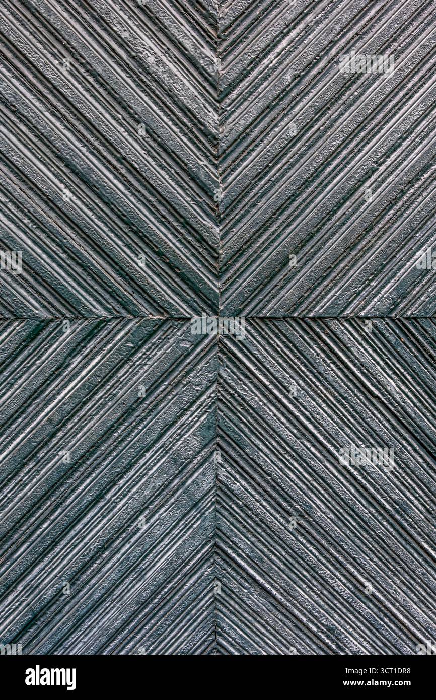Motif géométrique en chevrons sur porte en bois, texture à chevrons en gris et sarcelle. Détail architectural abstrait, conception symétrique, bois vintage Banque D'Images
