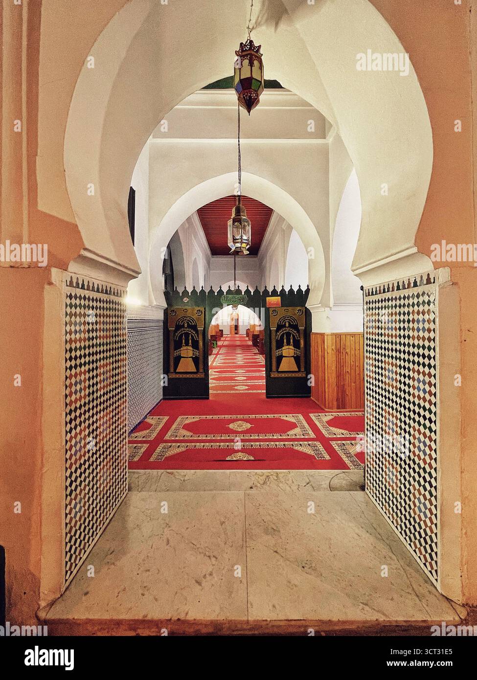 Entrée intérieure d'une mosquée dans l'ancienne médina de Tanger, Maroc. Portes arquées, tapis rouge et design islamique traditionnel. Tournage : 3 octobre 2025. Banque D'Images