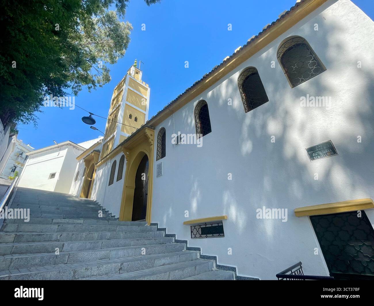 Escalier en pierre escarpé menant à une structure religieuse aux murs blancs avec des fenêtres cintrées et une tour élancée, Tanger, Maroc — 7 juin 2024. Banque D'Images