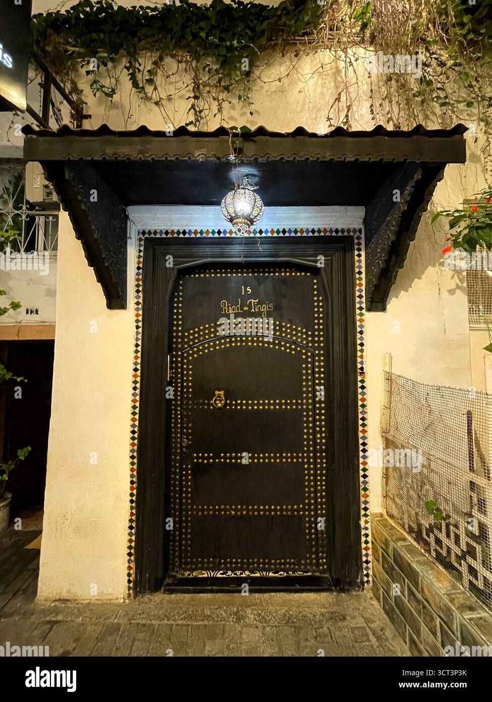 Porte noire décorative dans l'ancienne médina de Tanger, Maroc. Accents dorés, tuiles colorées et lanterne suspendue. Capturé le 2 octobre 2025. Banque D'Images