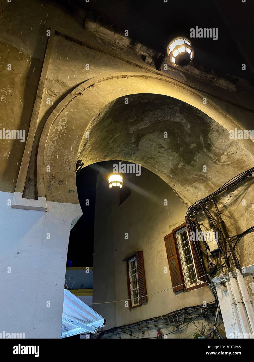 Arche historique dans l'ancienne médina de Tanger, Maroc. Éclairage nocturne, lanternes suspendues et architecture texturée. Capturé le 2 octobre 2025. Banque D'Images