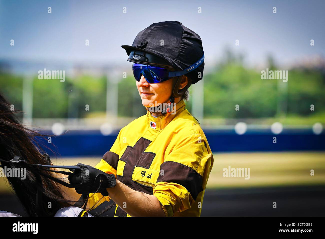 16.09.2025 Paris,Hippodrome de Vincennes.Jockey dans un casque noir et des lunettes bleues dans un uniforme jaune et noir se préparant à une course. Banque D'Images