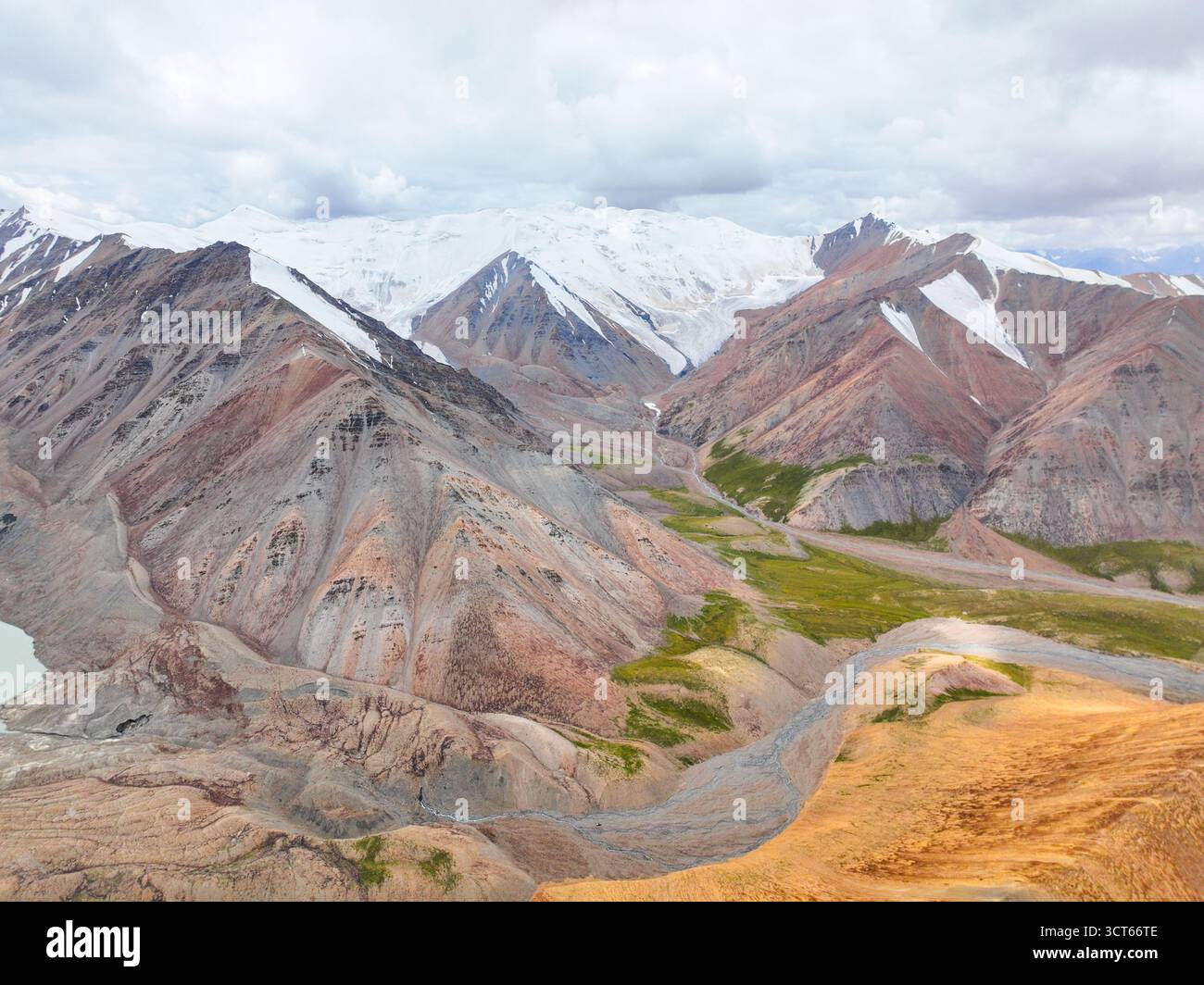Vue aérienne large d'une immense chaîne de montagnes colorée avec des sommets enneigés, un glacier en recul et une vallée accidentée en contrebas Banque D'Images