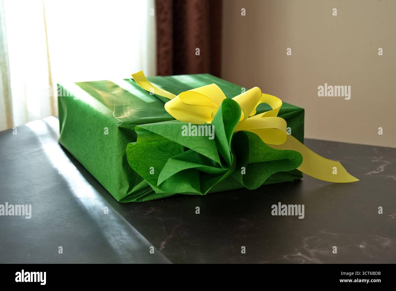 Cadeau enveloppé dans du papier vert avec ruban jaune sur la table Banque D'Images