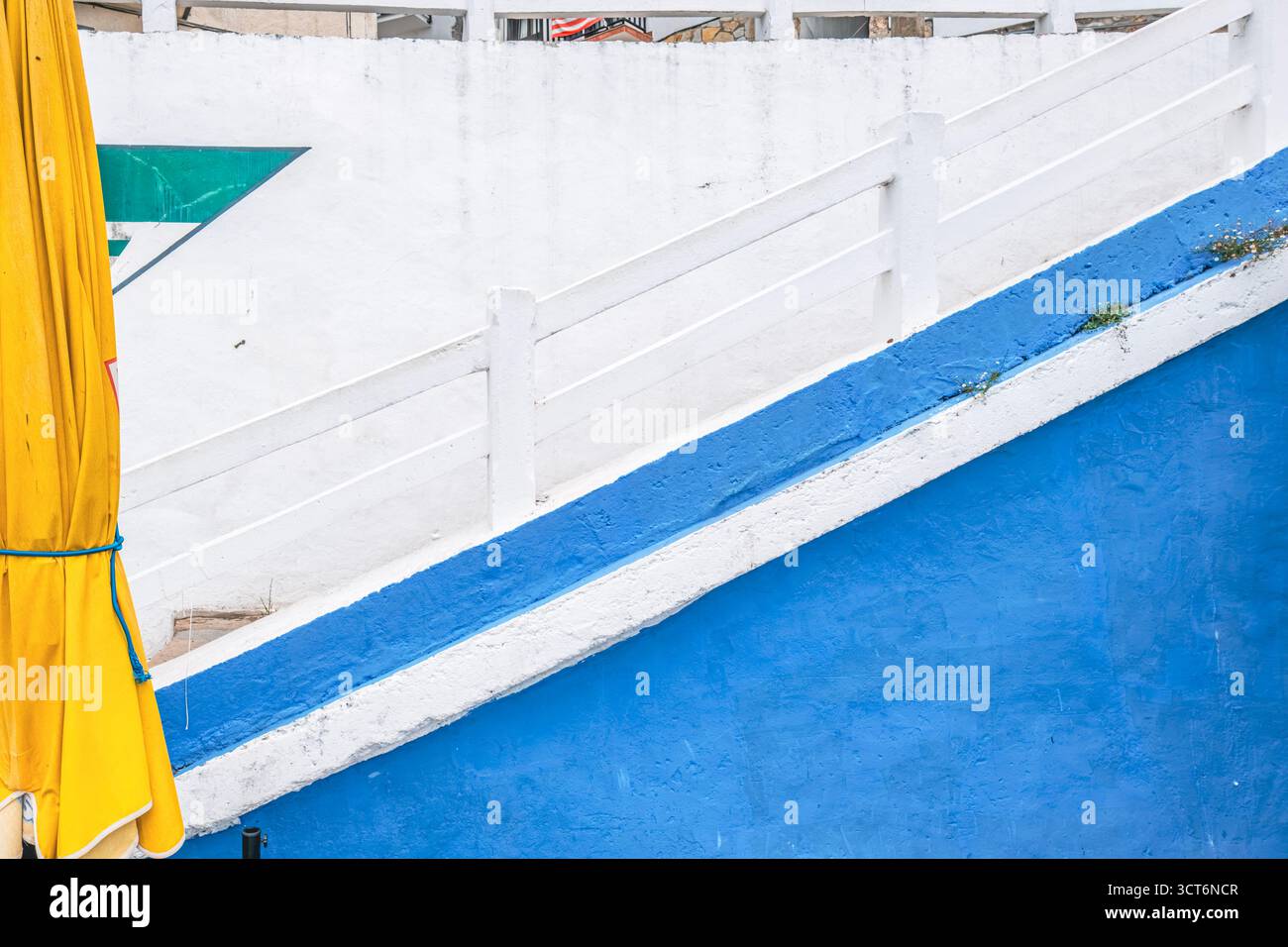 Architecture colorée avec des lignes géométriques bleues et blanches, détail d'auvent jaune, motif de mur abstrait, façade de bâtiment côtier, bandes diagonales Banque D'Images