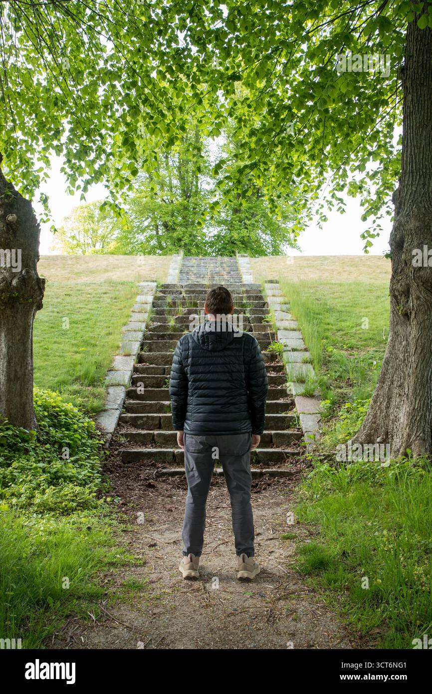 Homme debout devant og grand escalier en pierre montant pensant de quelle façon choisir, image symbolique, image verticale Banque D'Images