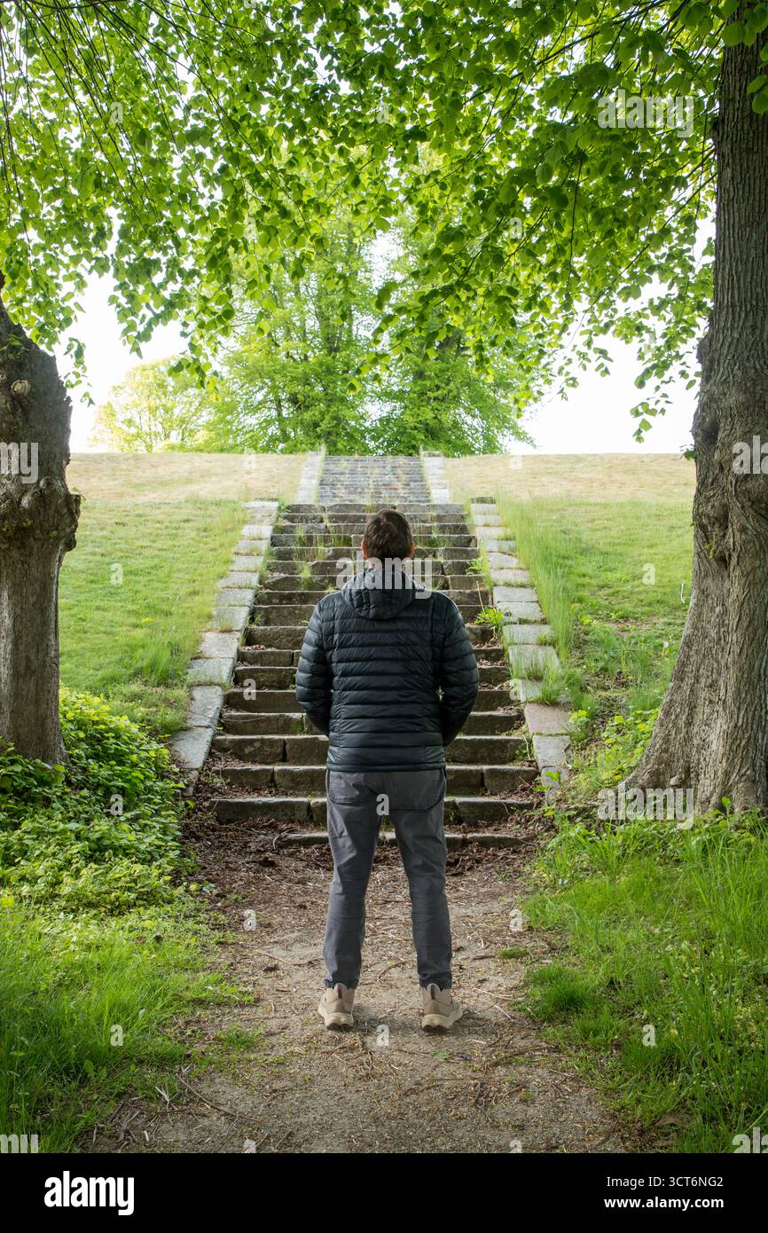 Homme debout devant og grand escalier en pierre montant pensant de quelle façon choisir, image symbolique, image verticale Banque D'Images