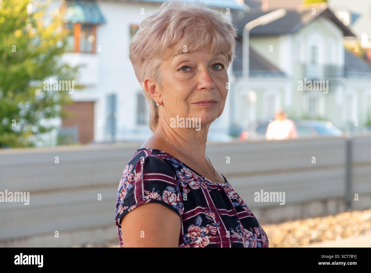 Une femme âgée de 65 70 ans dans une robe colorée se tient sur une plate-forme. Banque D'Images