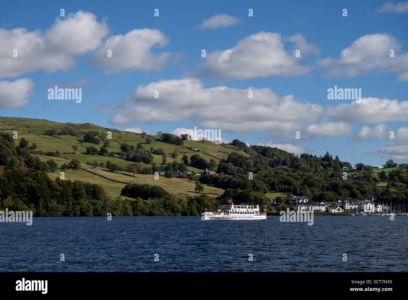Bateau de croisière naviguant sur le lac Windermere, Cumbria, avec collines boisées et campagne vallonnée dans le parc national du Lake District Banque D'Images