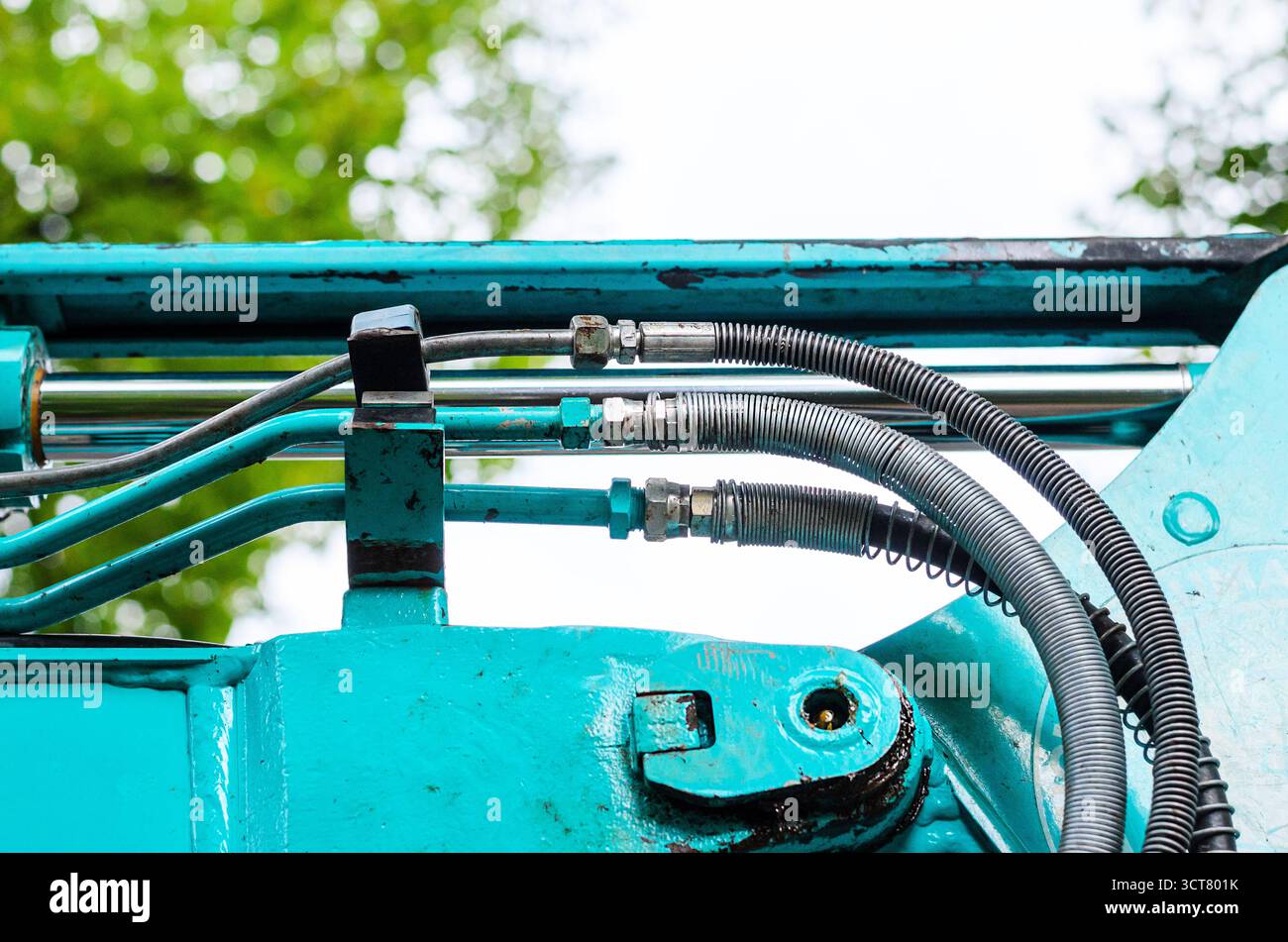 Gros plan sur le piston hydraulique turquoise brillant et les tuyaux industriels Banque D'Images