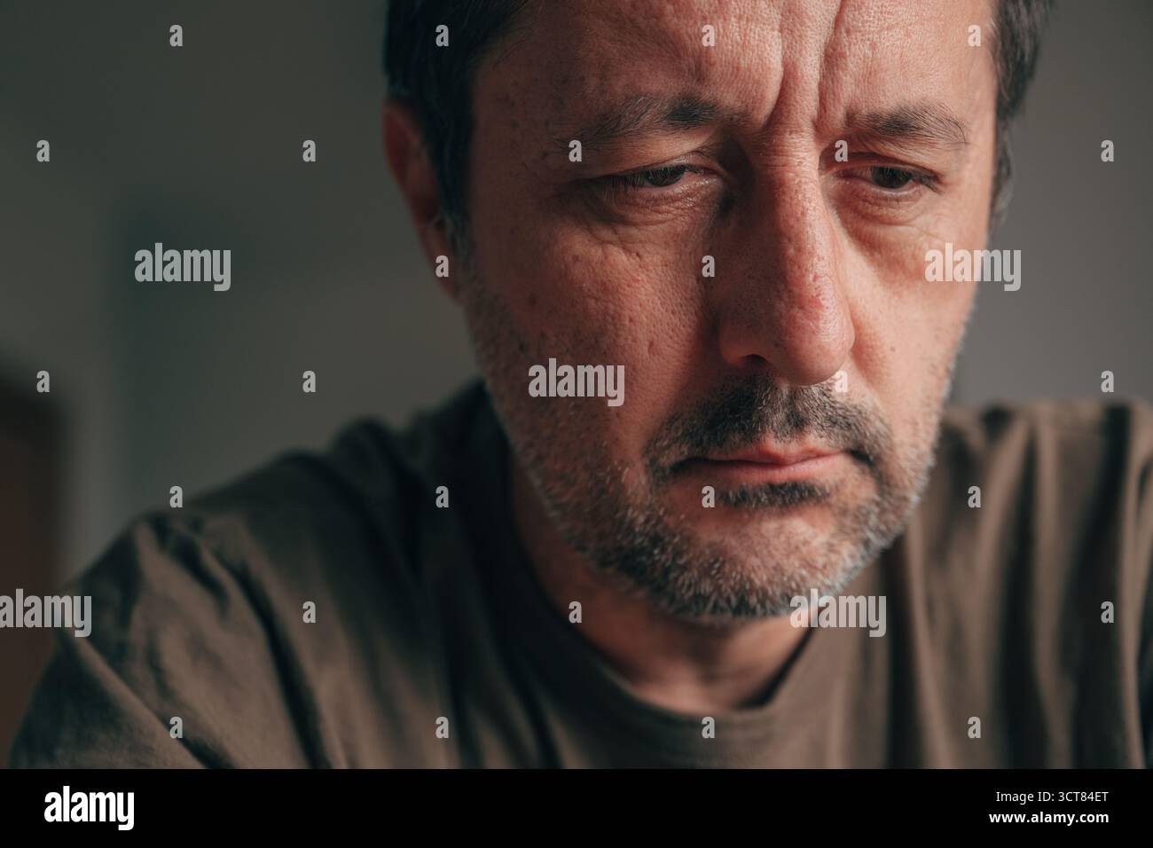 Gros plan portrait d'un homme adulte mûr découragé regardant vers le bas avec une expression triste. Mâle déprimé en gros plan, yeux rabaissés, conce Banque D'Images