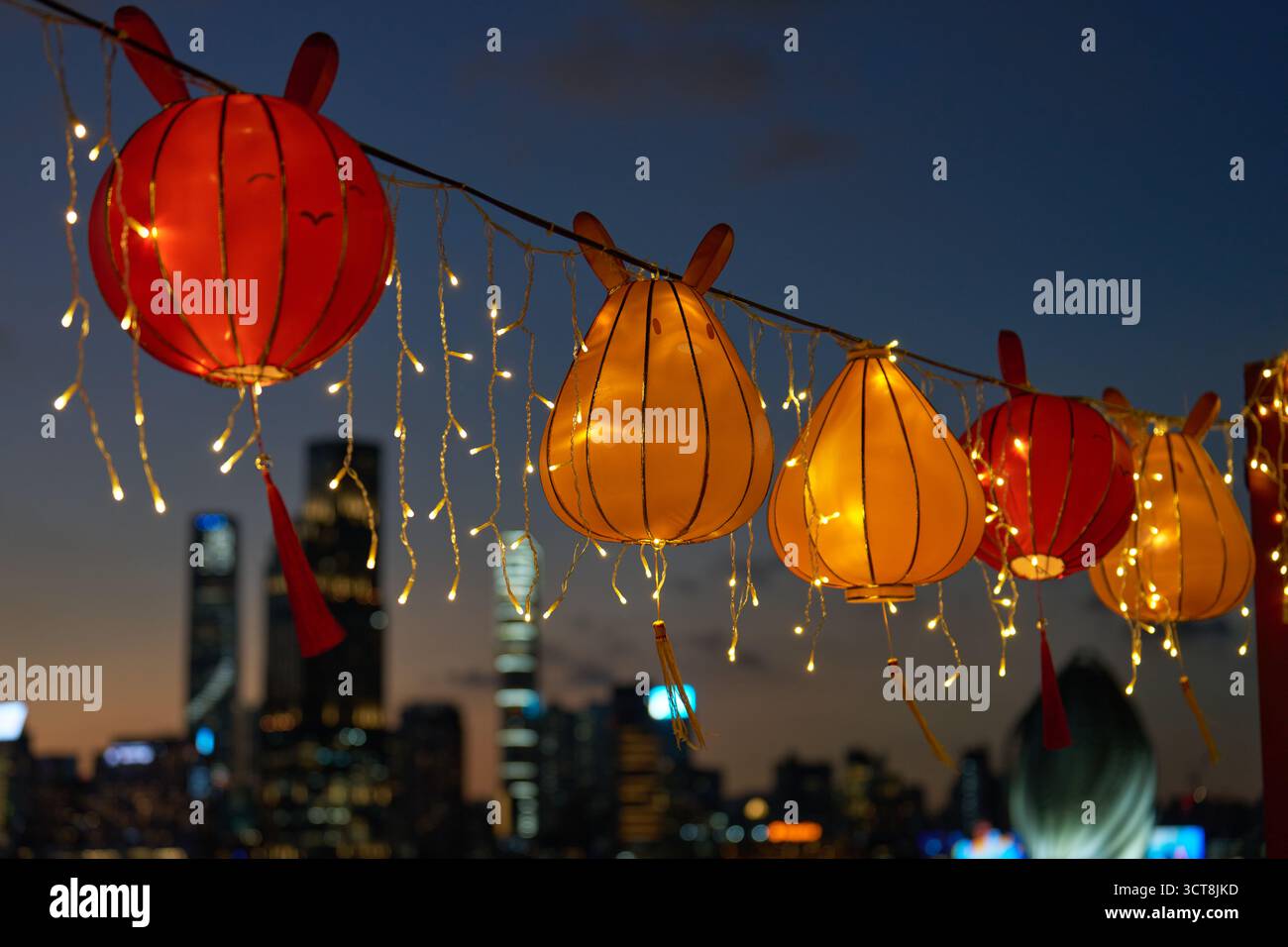 Tin Hau, Hong Kong - 2 octobre 2025 : lanternes rouges et oranges de différentes formes à East Coast Park Precinct contre Kowloon Coastal Dawn skyline. Banque D'Images