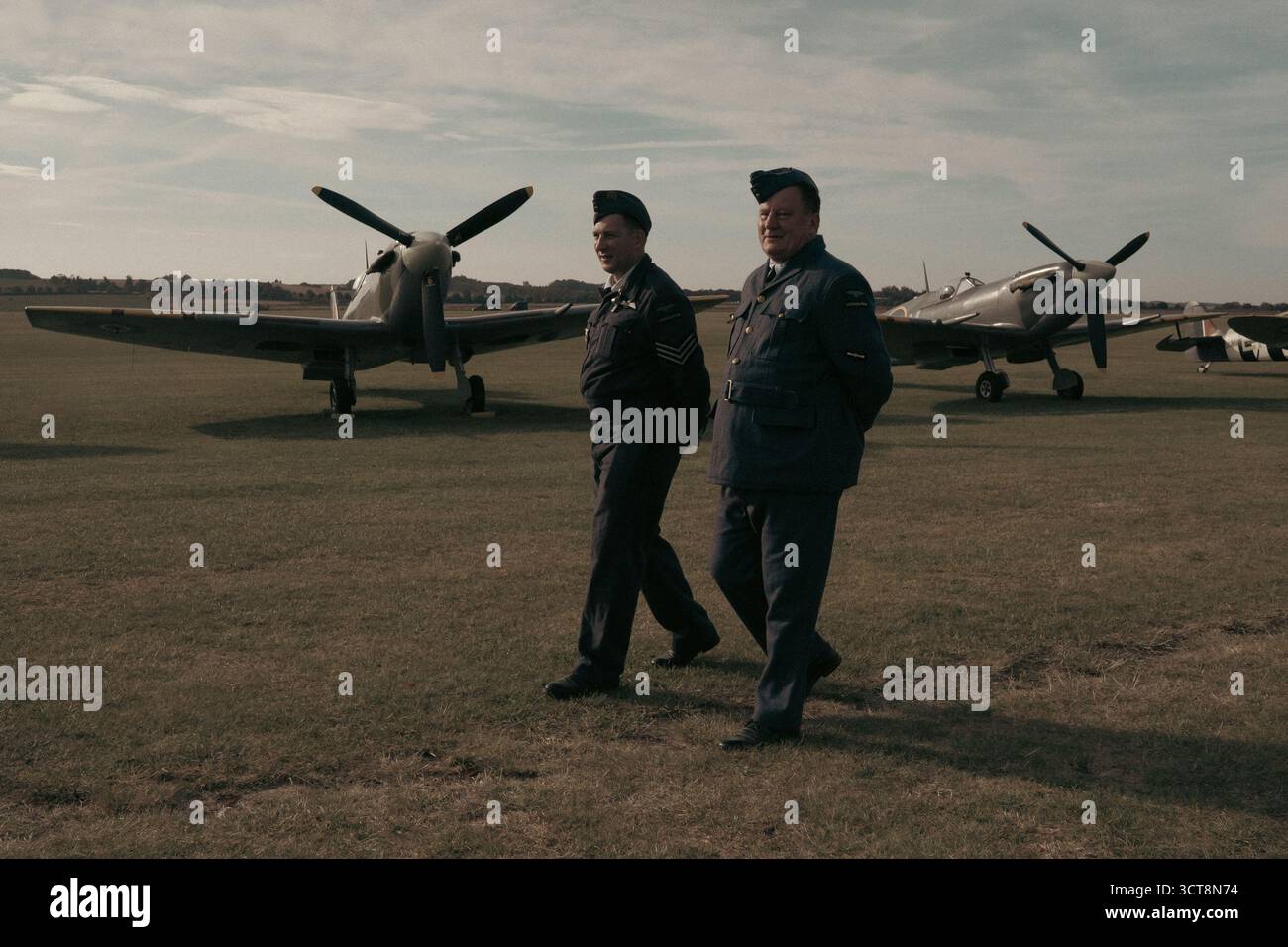 Deux pilotes de la RAF passant devant des avions Spitfire à l'aérodrome historique Banque D'Images