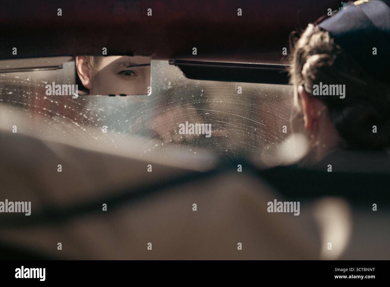 Oeil de femme réfléchi dans le rétroviseur de la voiture avec des gouttes de pluie sur le pare-brise Banque D'Images