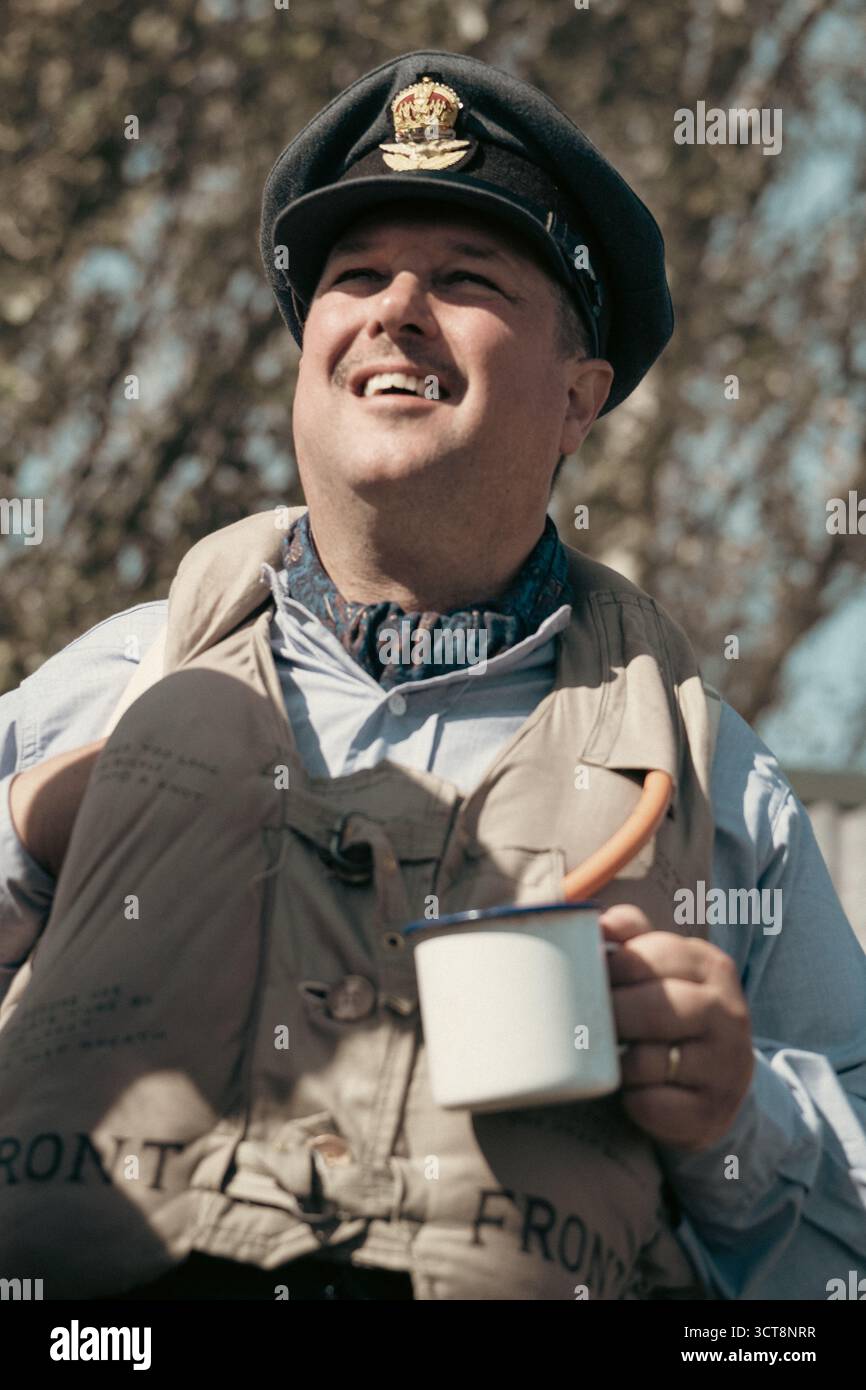 Pilote de la RAF en uniforme souriant tout en tenant une tasse en émail au spectacle aérien de Duxford Banque D'Images