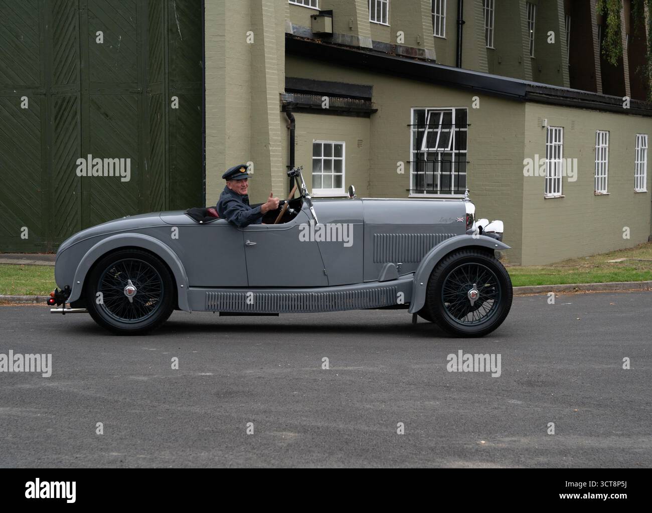 Voiture de sport gris vintage avec chauffeur en costume d'époque à l'aérodrome de Duxford Banque D'Images