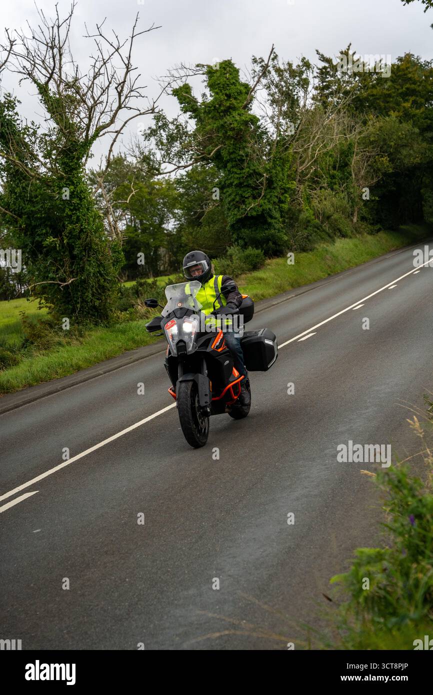 Motocycliste en veste haute visibilité chevauchant le vélo d'aventure sur la route rurale de l'île de Man Banque D'Images