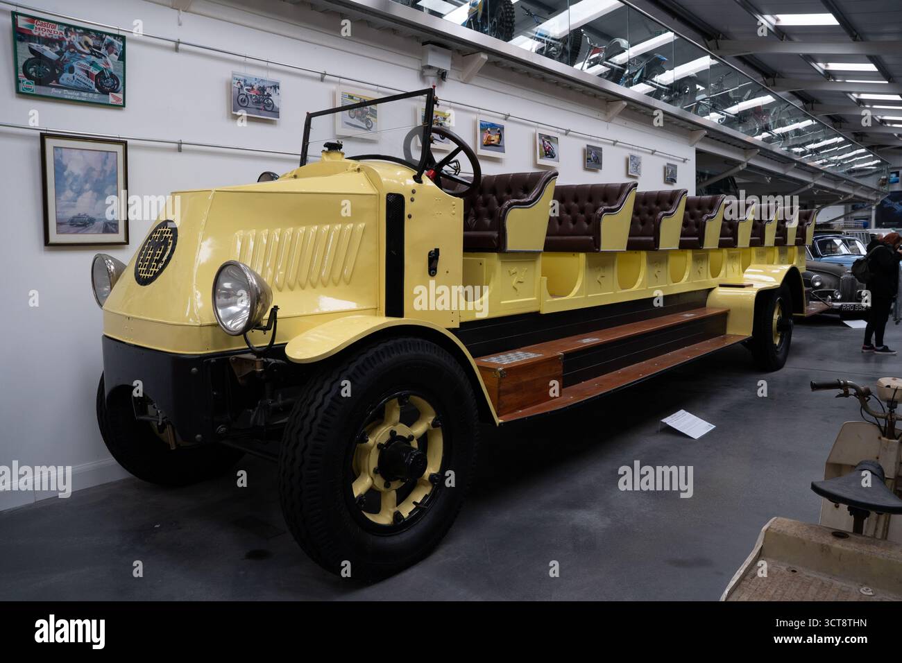 Vintage jaune véhicule multi-passagers exposé dans le musée des transports avec des motos sur les murs Banque D'Images