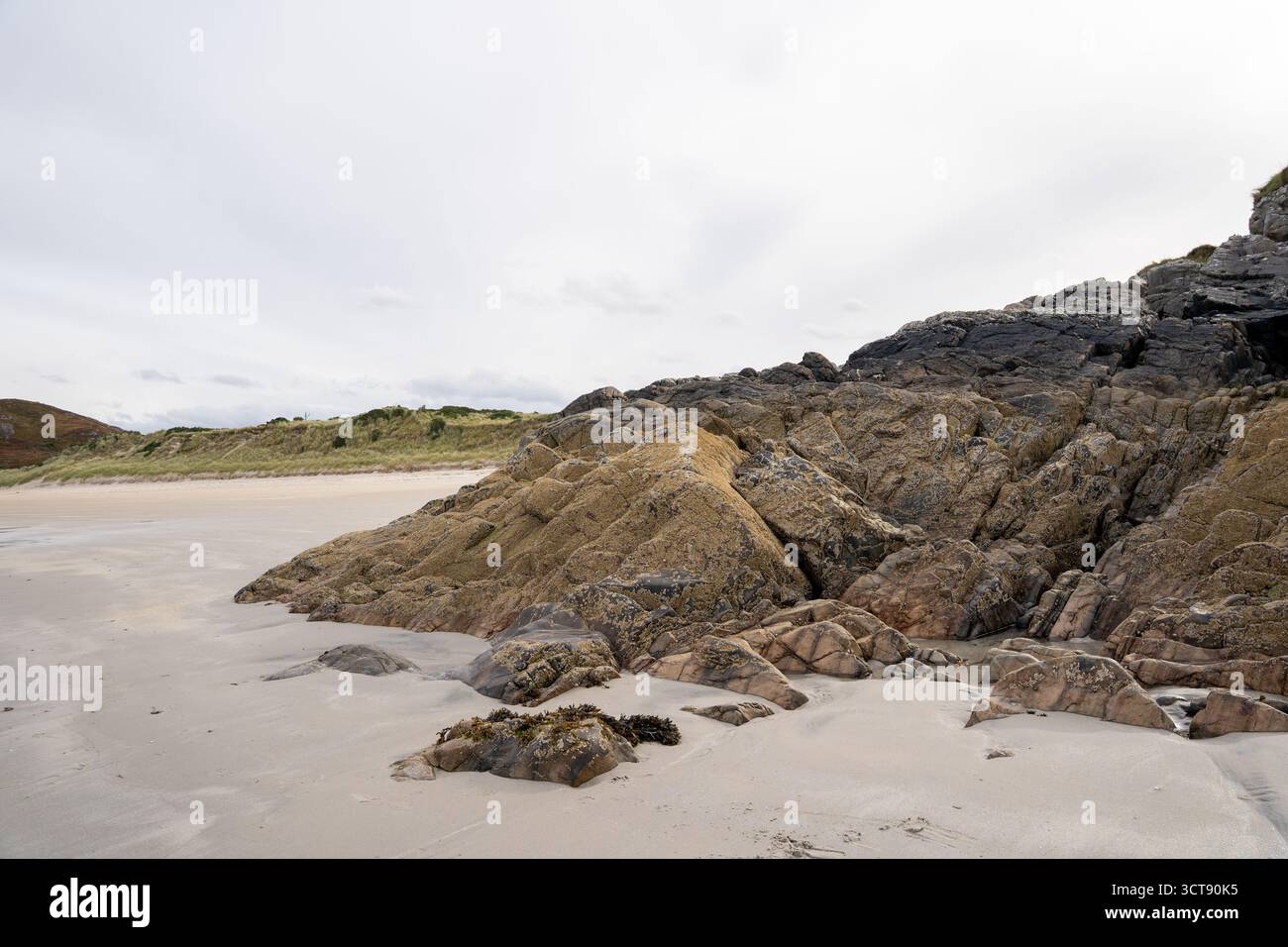 Affleurements rocheux sur une plage écossaise immaculée avec du sable doré et des paysages côtiers Banque D'Images