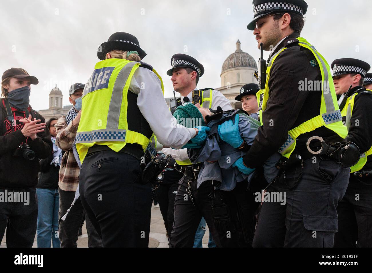 Londres, Royaume-Uni. 4 octobre 2025. Des policiers de la Metropolitan police arrêtent un manifestant qui avait une pancarte indiquant « je m'oppose au génocide, je soutiens l'action palestinienne » lors d'une veillée silencieuse de masse à Trafalgar Square organisée par Defend Our Jurys dans le cadre de sa campagne Lift the Ban contre la prohibition du groupe d'action directe Palestine action. Environ 1 000 personnes ont assisté à l'événement et la police métropolitaine, assistée de plusieurs autres forces de police, a procédé à 492 arrestations, dont 488 pour soutien à une organisation interdite. Crédit : Mark Kerrison/Alamy Live News Banque D'Images
