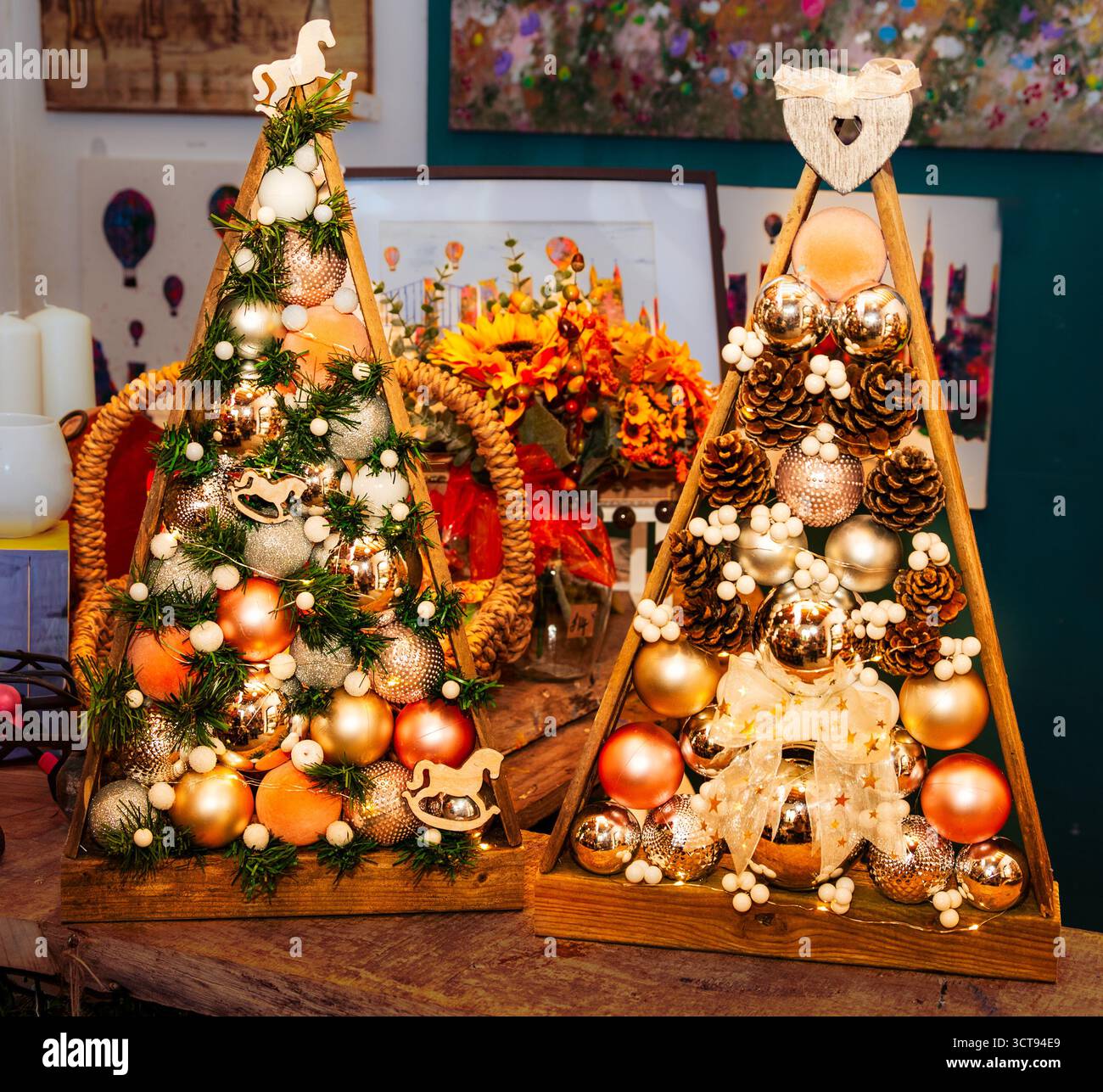 Décor festif de vacances ! Ces arbres de Noël en bois faits à la main sont ornés d'ornements, de pommes de pin et de lumières pour un charme unique et rustique. Banque D'Images