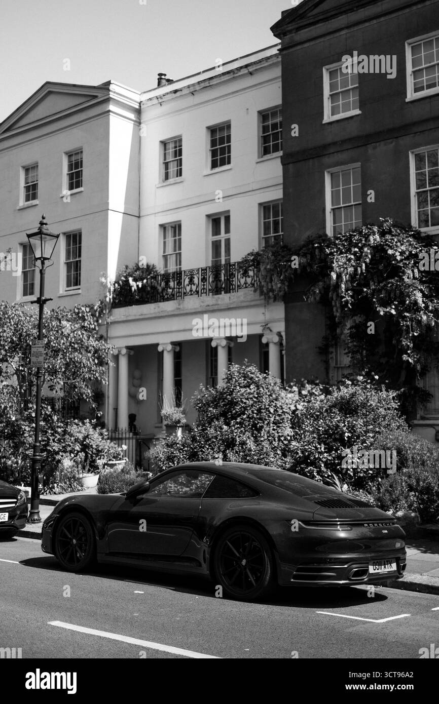 Chiswick, Londres – 2025.04.28 – Une Porsche 911 noire garée le long d’une rue résidentielle calme bordée de maisons de style géorgien et d’une végétation luxuriante, captur Banque D'Images
