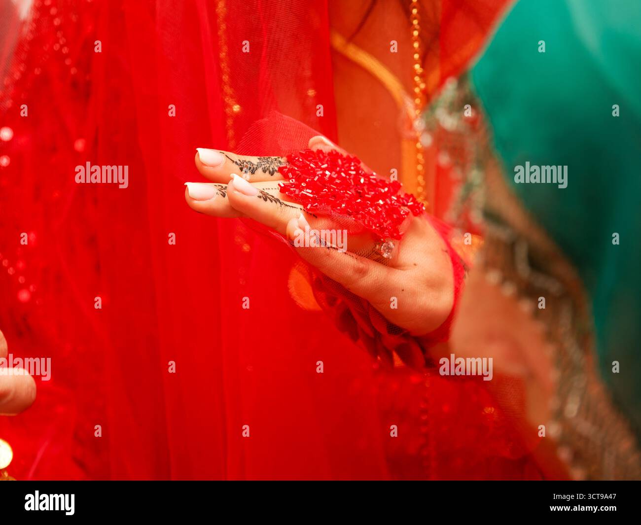 Henné sur la main de la mariée sous voile rouge pendant le rituel de mariage. Banque D'Images