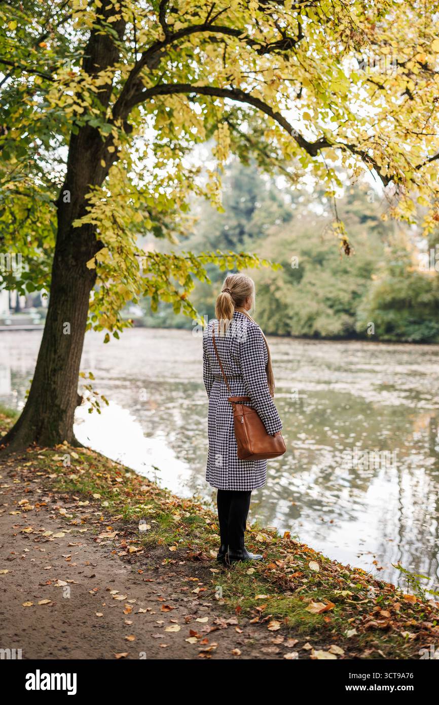 Femme pensive debout dans le parc d'automne, exprimant la mélancolie et l'humeur réfléchie Banque D'Images