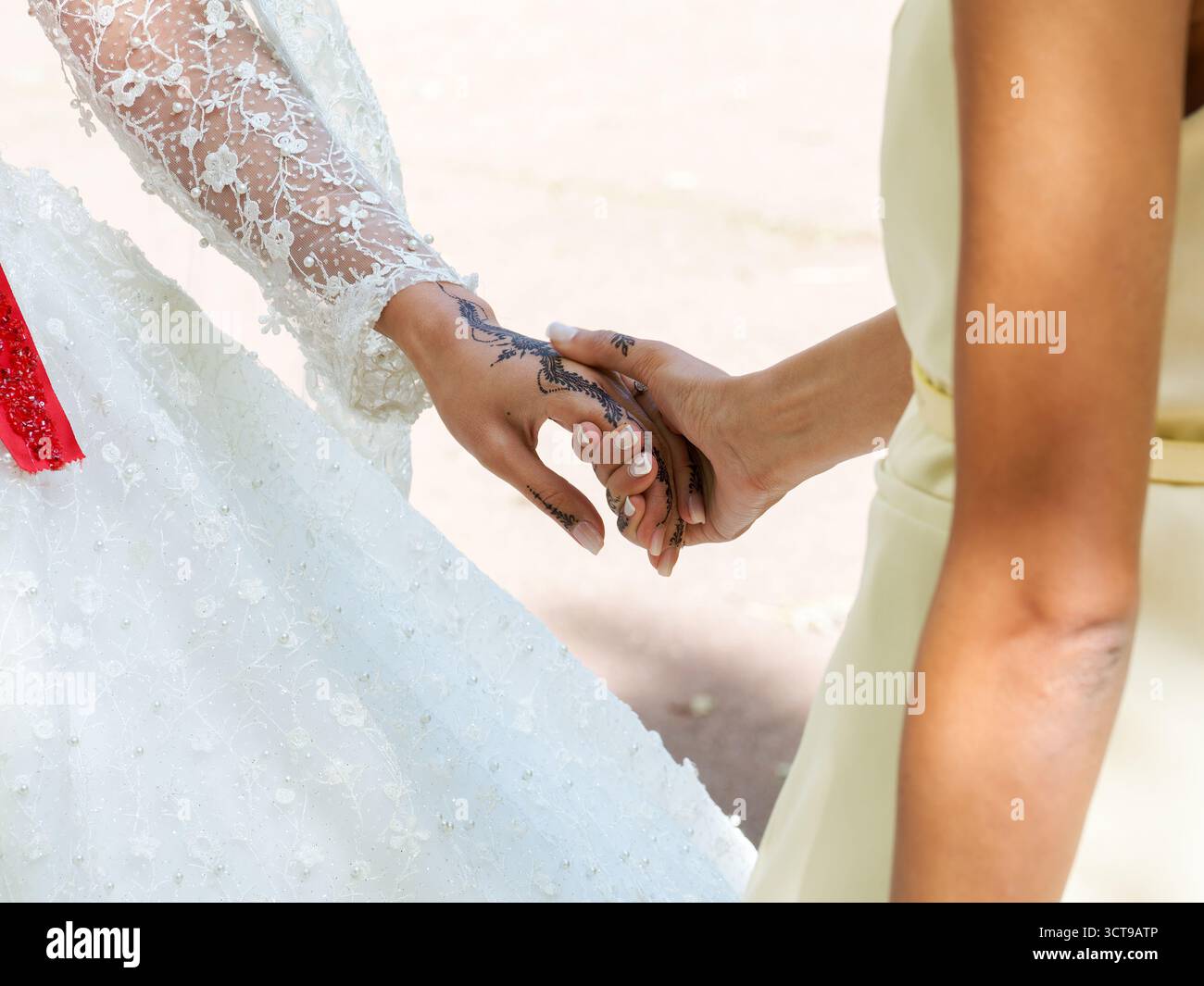 Mains de la mariée avec du henné reposant sur la robe perle blanche lors de la cérémonie de mariage à Paris. Banque D'Images