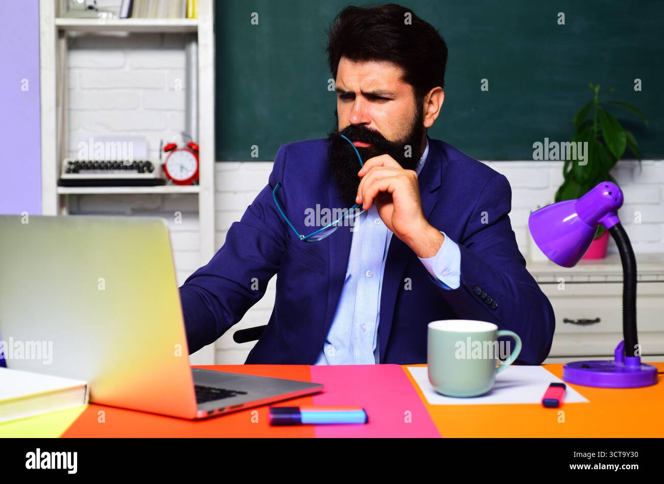 Professeur masculin, homme d'affaires, employé de bureau travaillant avec ordinateur portable au lieu de travail. Étudiant sérieux se préparant à l'examen à l'aide d'un ordinateur portable en classe. Cours en ligne Banque D'Images