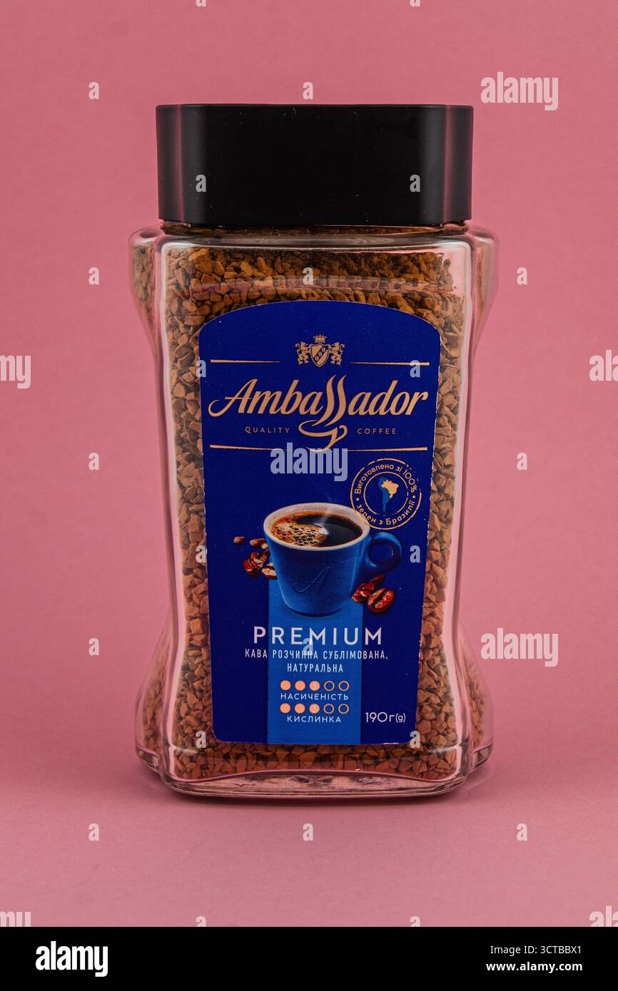 Le café instantané est présenté dans un récipient transparent avec une étiquette bleue sur fond rose, soulignant sa qualité et ses caractéristiques premium. Banque D'Images