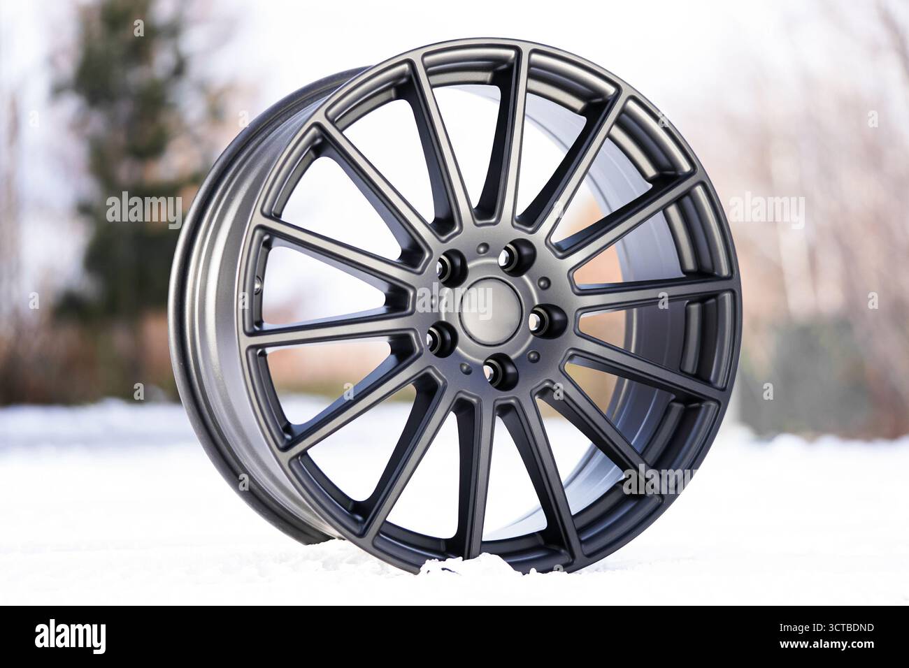 Les jantes en alliage élégantes sont bien en évidence, avec un design contemporain à rayons multiples. la roue est placée sur un fond enneigé, réfléchissant Banque D'Images