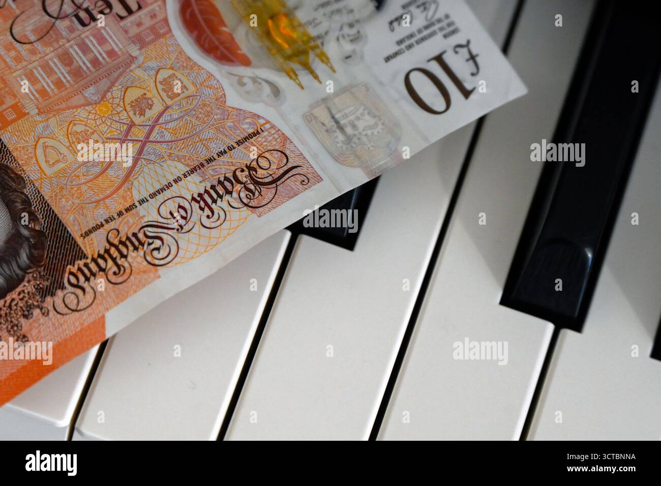 Billets de banque britanniques posés sur le clavier de piano Banque D'Images