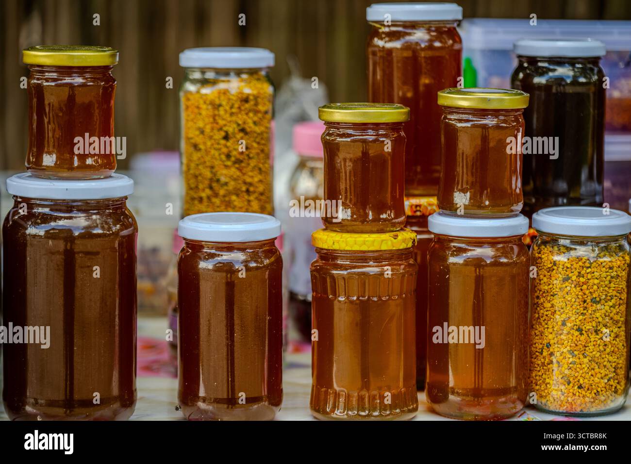 Des bocaux en verre remplis de miel naturel et de pollen d'abeille sont exposés à la vente sur un marché local à Qabala, en Azerbaïdjan. Banque D'Images