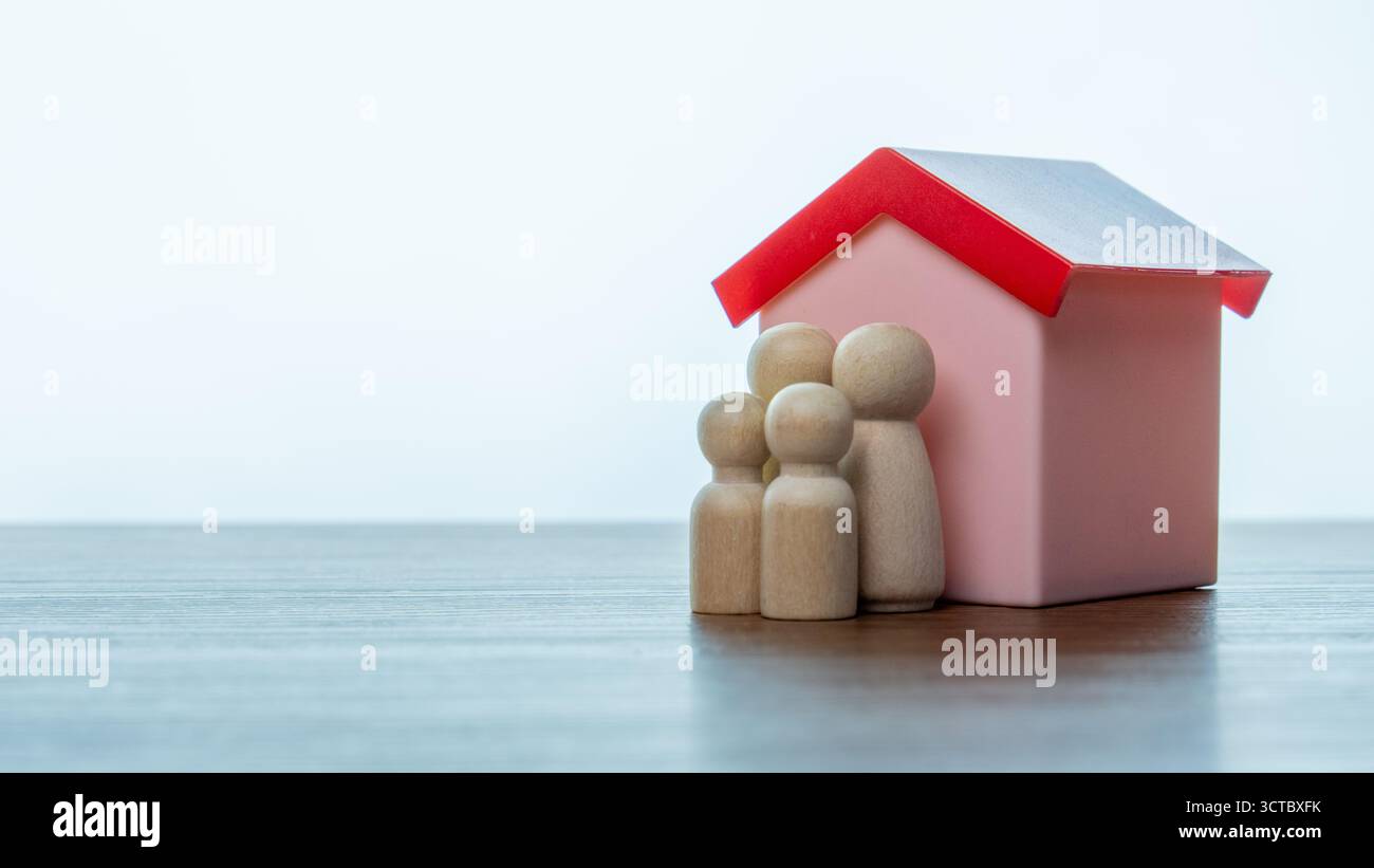 Concept de soins familiaux, de protection et d'assurance. Famille de poupées en bois et une maison. Copier l'espace pour le texte. Banque D'Images