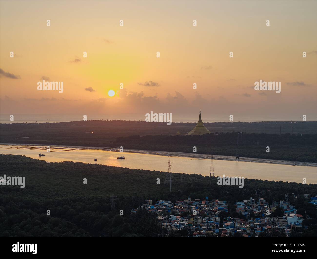 Vue aérienne d'un soleil doré coulant sur la Pagode Global Vipassana, projetant une lueur chaude sur les eaux et le bord de la ville, Mumbai, Maharashtra, Inde. Banque D'Images