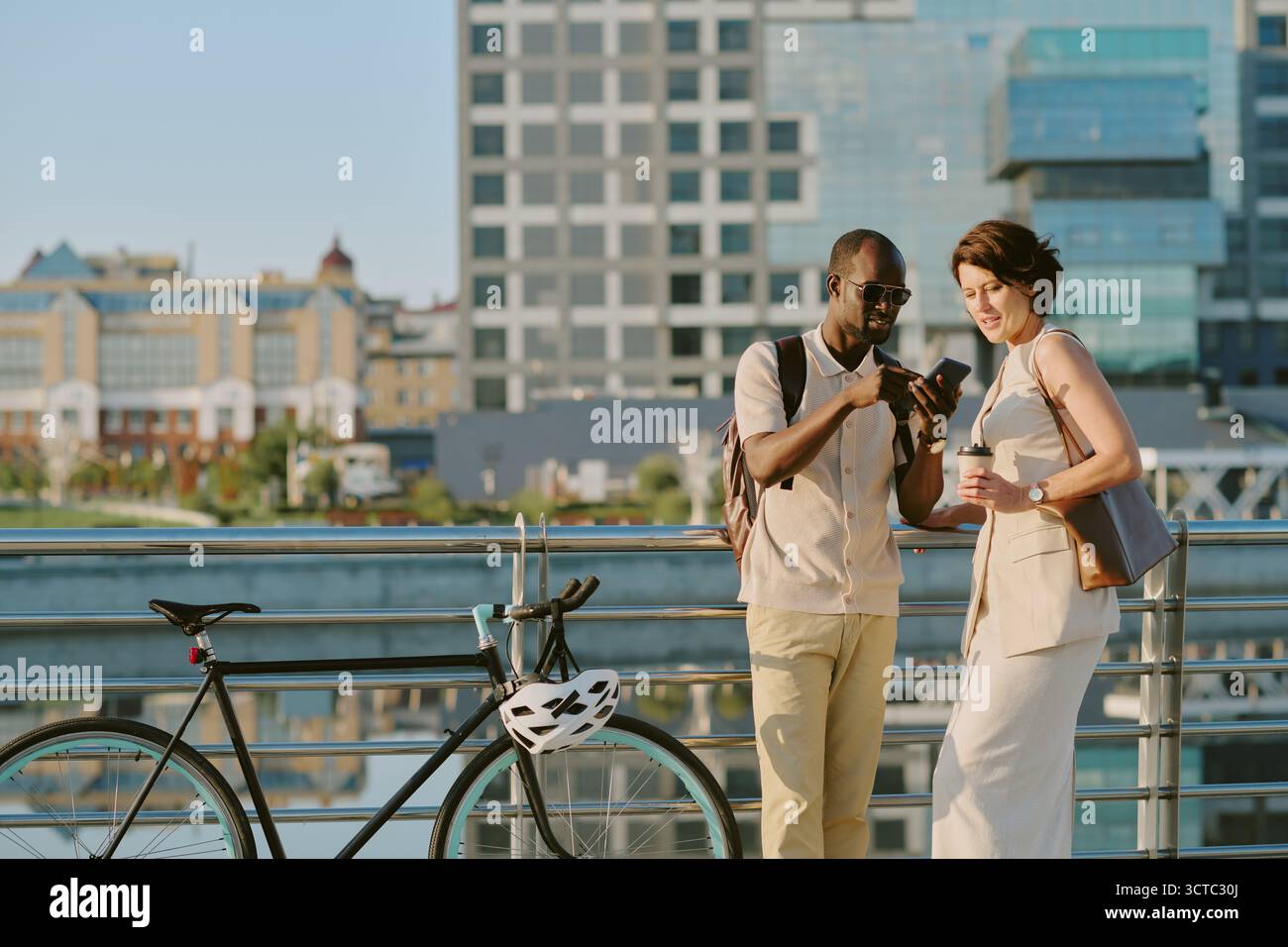 Jeune homme noir adulte et femme caucasienne utilisant smartphone à l'extérieur ensemble Banque D'Images