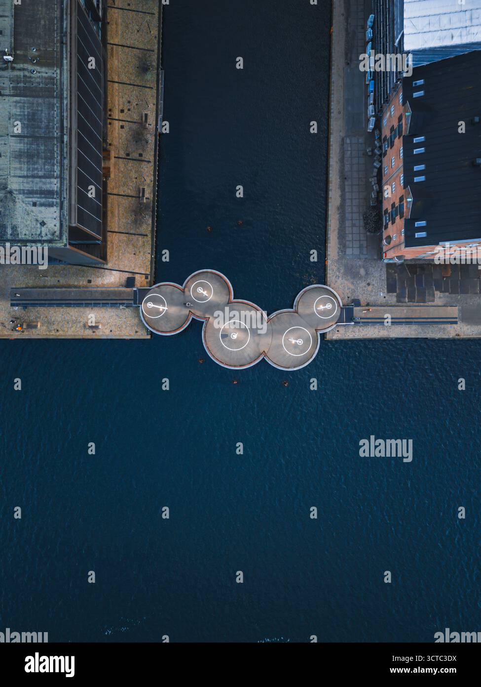 Vue aérienne de l'eau sombre reflétant le ciel autour de la conception architecturale unique du Circle Bridge, Copenhague, Danemark. Banque D'Images