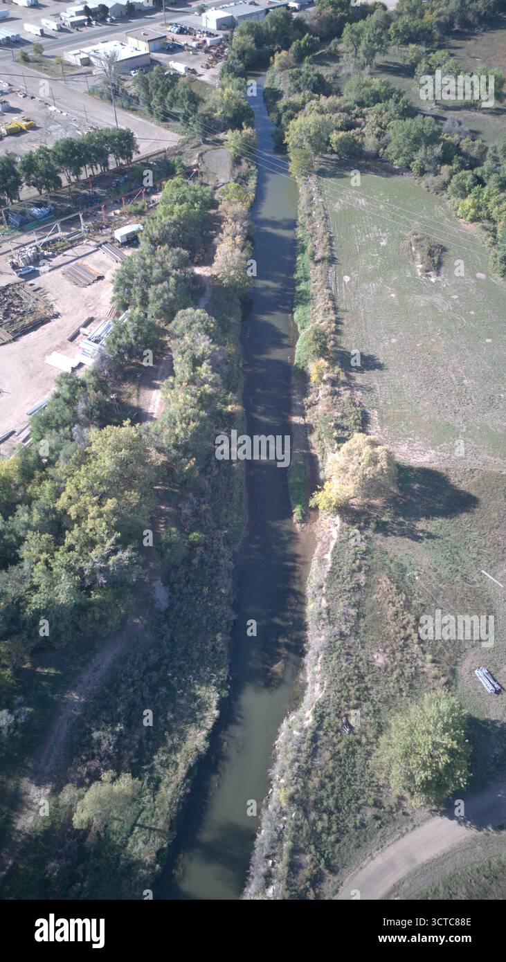 Vue aérienne de la rivière cache la poudre coupant à travers le paysage, avec des arbres bordant ses rives et ses champs s'étendant au-delà, Greeley, Colorado, États-Unis. Banque D'Images