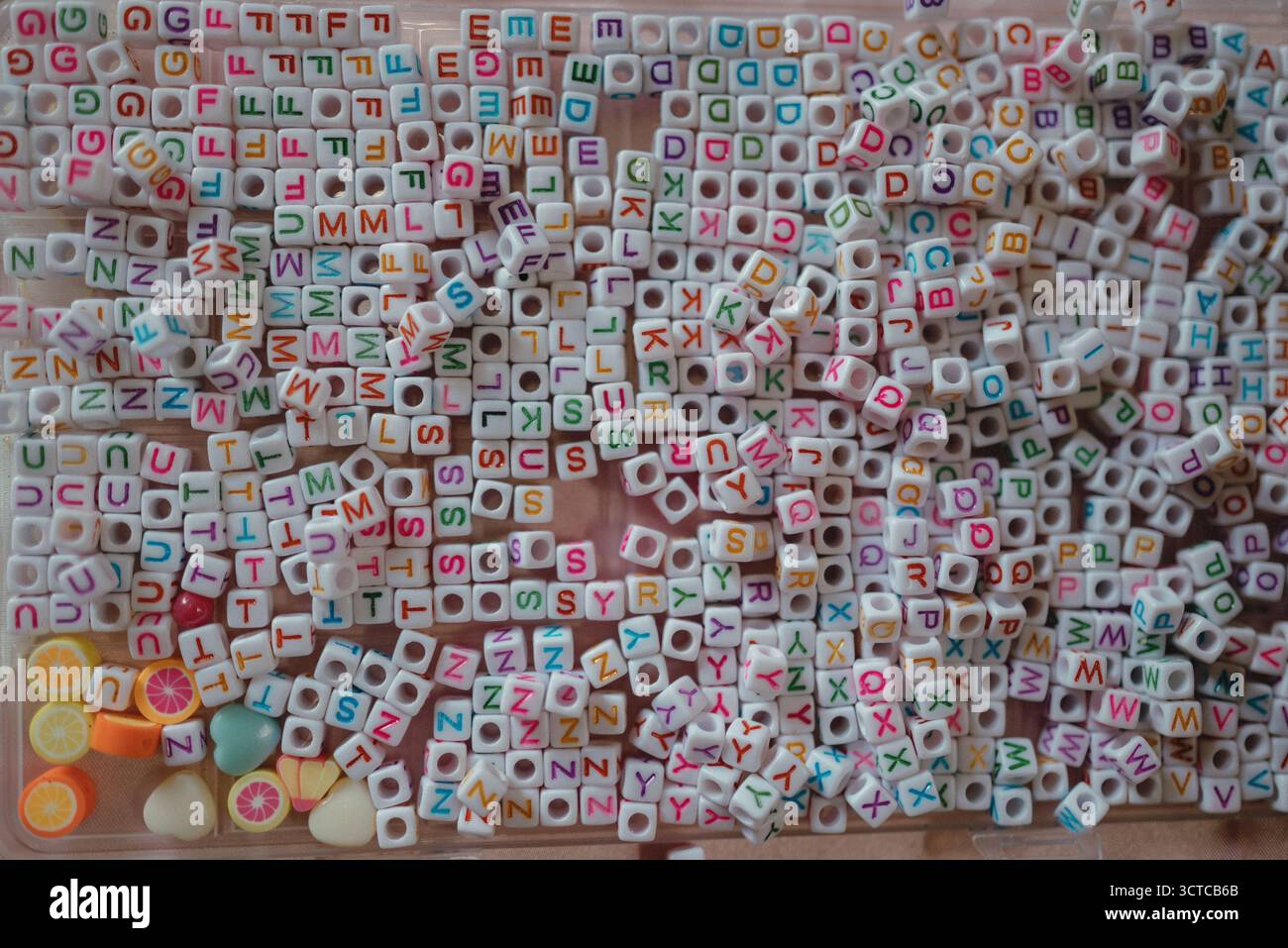Un assortiment coloré de perles de lettres et de breloques en forme de fruits Banque D'Images