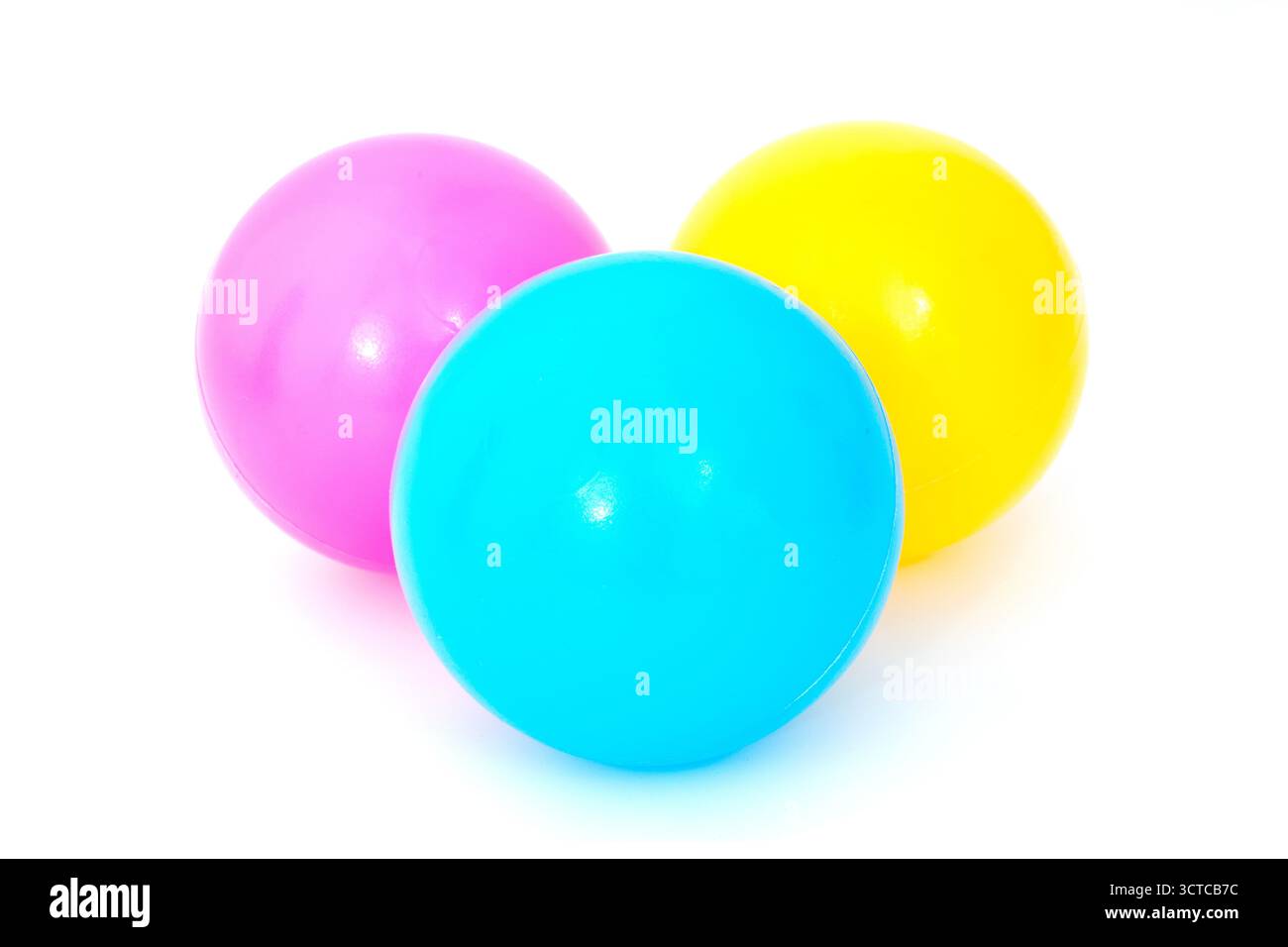 Trois balles de jeu en plastique bleu, jaune et rose sur fond blanc Banque D'Images