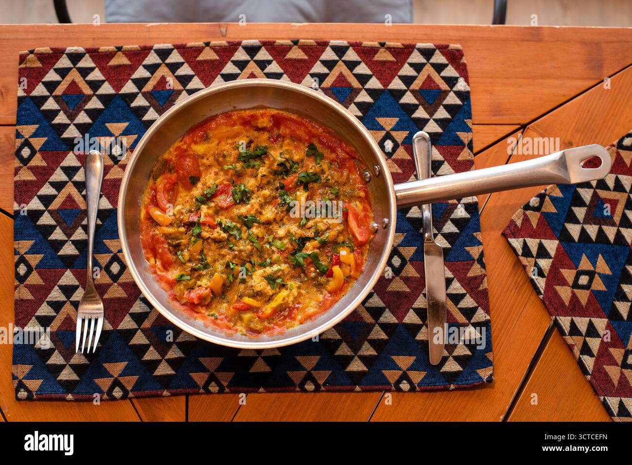Shakshuka coloré dans une casserole sur tapis de table à motifs Banque D'Images