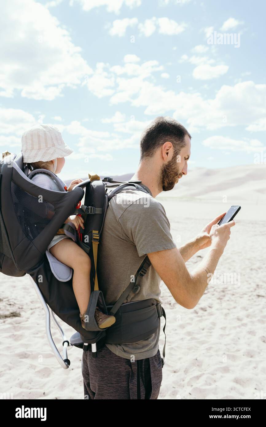 Garçon en bas âge assis dans un porte-sac à dos de randonnée pendant une randonnée Banque D'Images