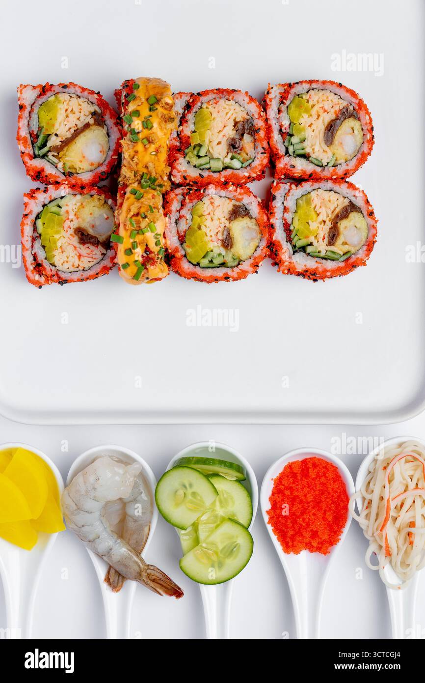 Rouleau de sushi de crevettes avec des ingrédients sur un fond blanc isolé Banque D'Images