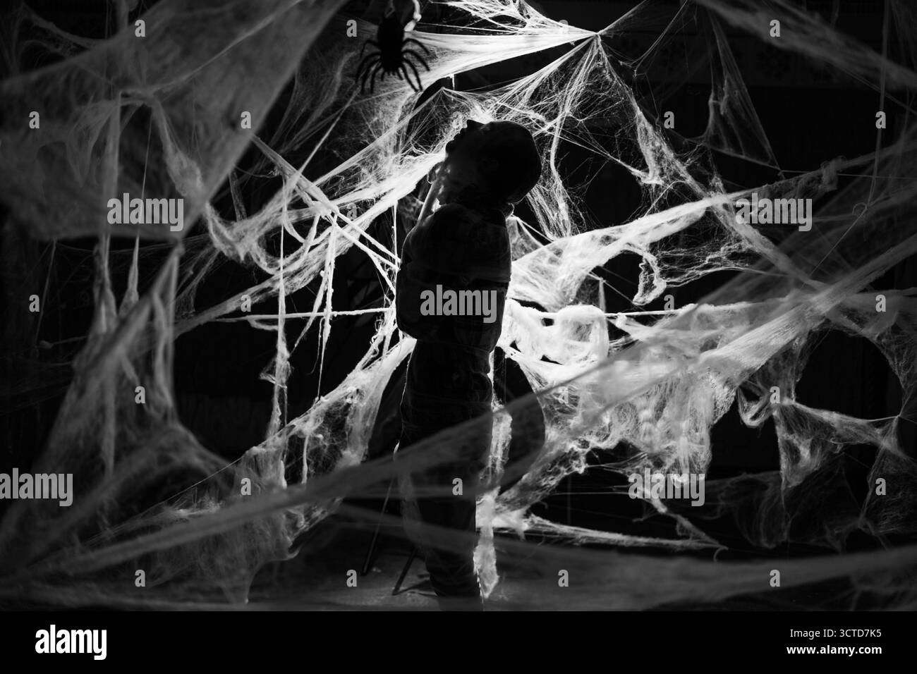 Homme effrayant avec le maquillage zombie d'Halloween effrayant piégé des toiles d'araignée, essayant de faire peur. Mec mort dans le web de cob sur fond sombre. photo noir et blanc. cop Banque D'Images