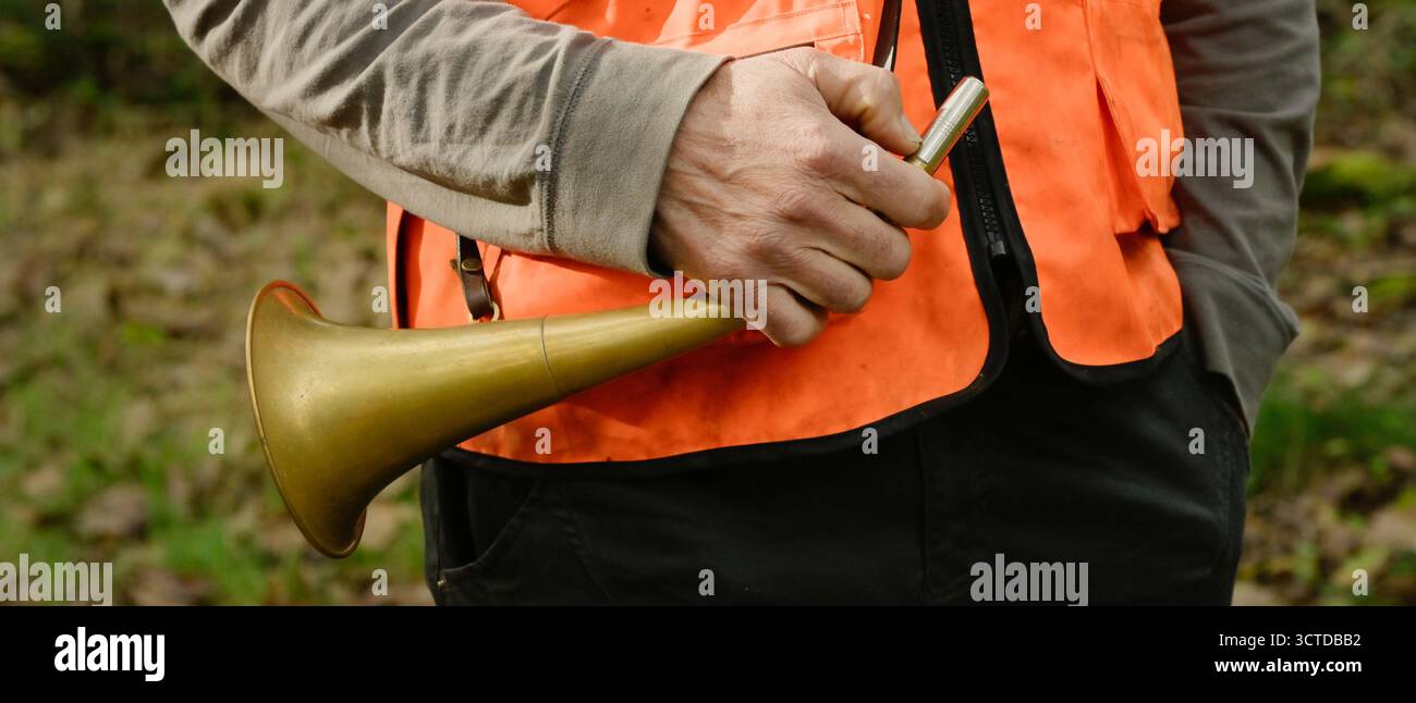 Gros plan de la main d'un chasseur tenant un pibole rond, une corne de chasse utilisée pour appeler pendant la chasse, forme de bannière Banque D'Images