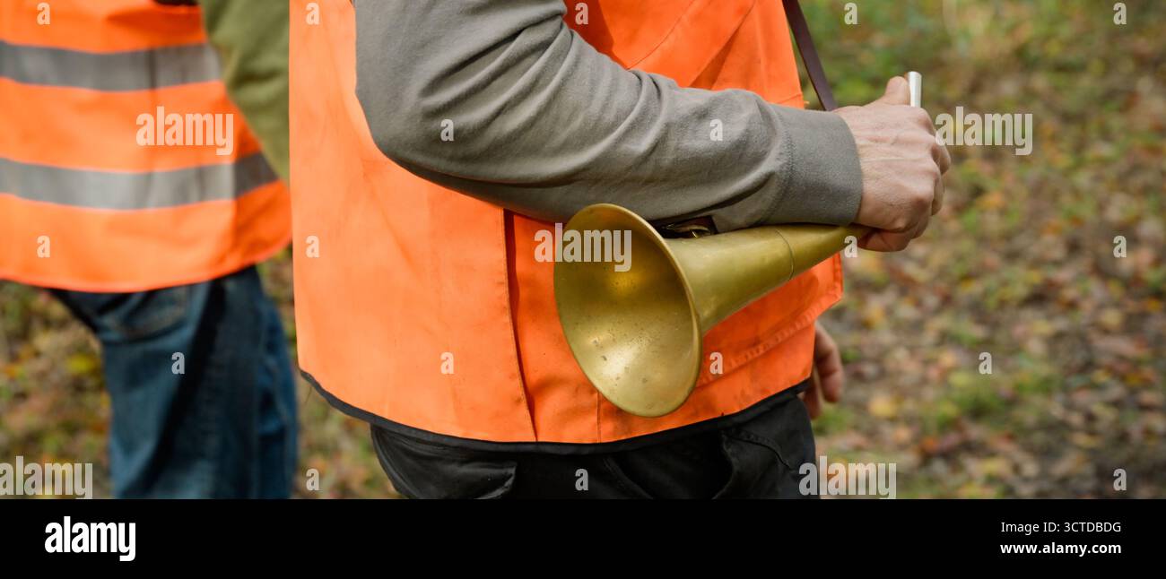 Gros plan de la main d'un chasseur tenant un pibole rond, une corne de chasse utilisée pour appeler pendant la chasse, forme de bannière Banque D'Images