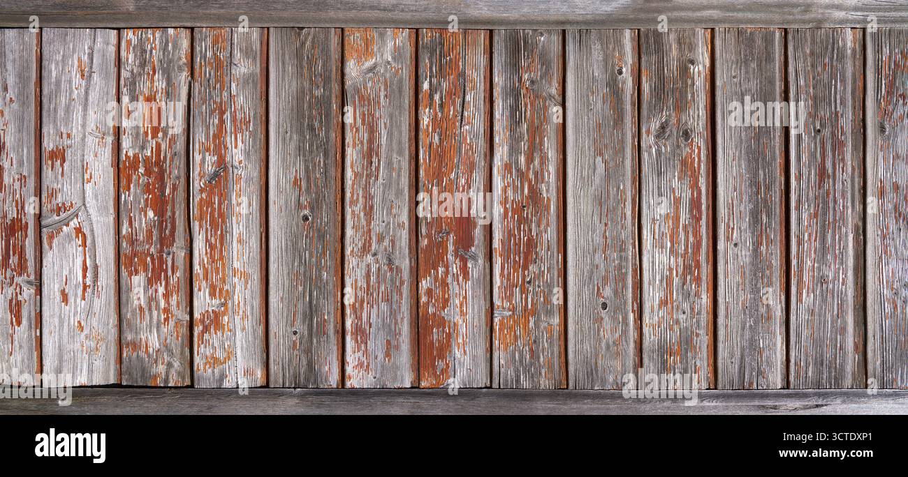 Vieux mur en bois fait de planches verticales grises altérées avec peinture orange pelable Banque D'Images