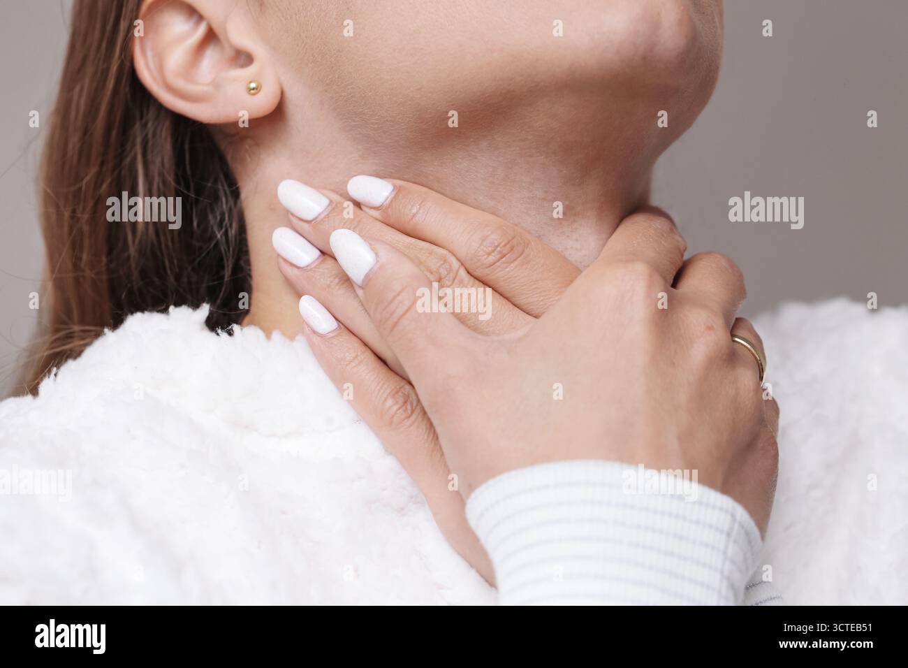 Femme touchant son cou souffrant de mal de gorge. Symptôme de grippe ou de rhume avec douleur et inflammation dans les amygdales. Problème de santé et maladie saisonnière. Banque D'Images